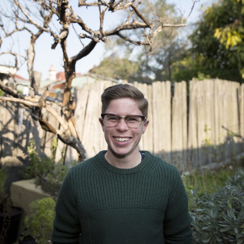 Katie Morrison smiling in a garden, wearing a dark green jumper